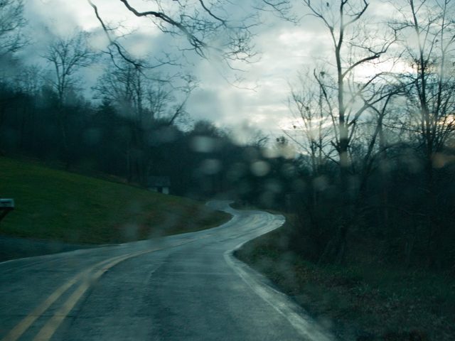 A road bending down a green hillside